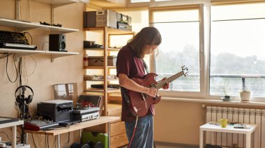 Elektro gitarda riff çalan konsantre bir adam.