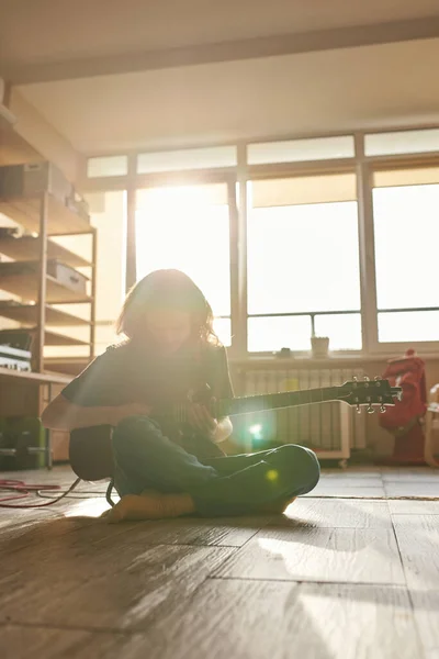 Muž hraje elektrickou kytaru na podlaze v slunném domě — Stock fotografie