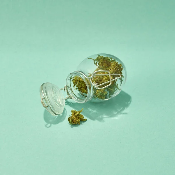 Відкрита скляна банка з сушеними марихуановими бруньками — стокове фото