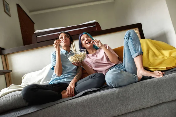 Joven pareja lesbiana viendo televisión y comiendo palomitas de maíz —  Fotos de Stock