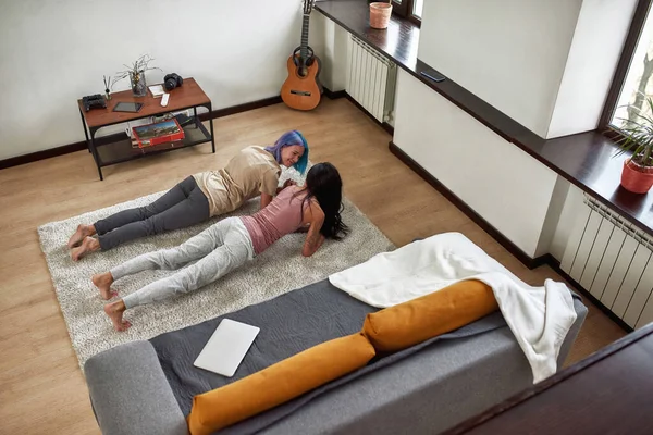 Vrolijke vrouwen die thuis op tapijt trainen — Stockfoto