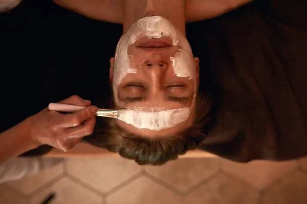 Cosmetician aplicando creme cosmético no rosto do homem — Fotografia de Stock