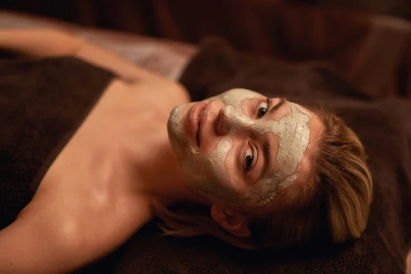Meisje met klei masker op gezicht in spa salon — Stockfoto