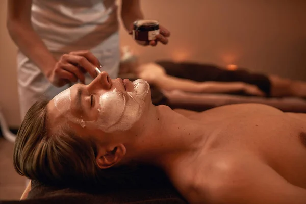 Cultivado de cosmetician aplicando creme no rosto do homem — Fotografia de Stock