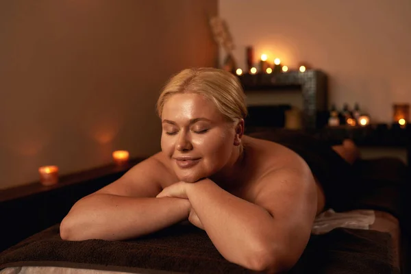 Mulher com olhos fechados descansando na mesa de massagem — Fotografia de Stock