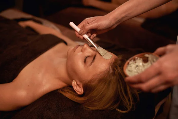 Cosmetician aplicando máscara de barro no rosto da mulher — Fotografia de Stock