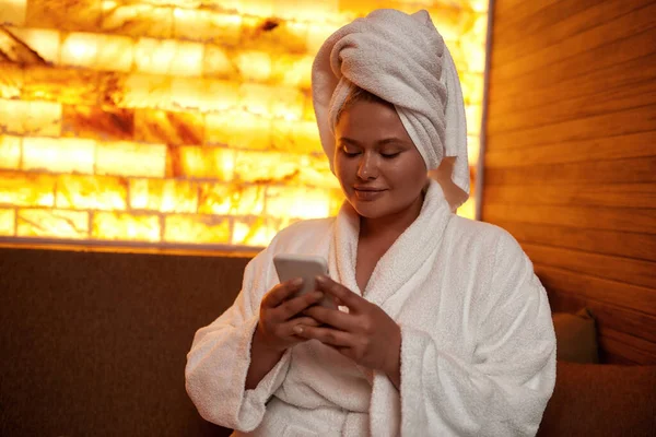Menina usando e assistindo no smartphone no salão de spa — Fotografia de Stock