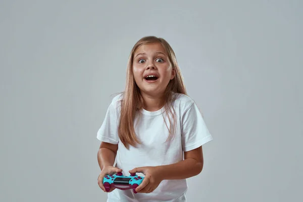 Überraschtes Mädchen spielt Videospiel mit Joystick — Stockfoto