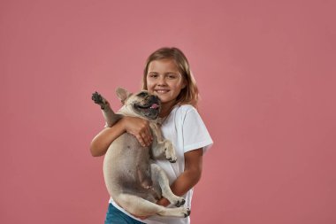 Güzel sarışın kız Fransız bulldog 'unu tutuyor.