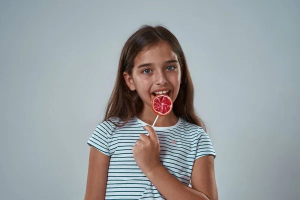 Partial of joyful little girl licking sweet lollipop — Stock Photo, Image