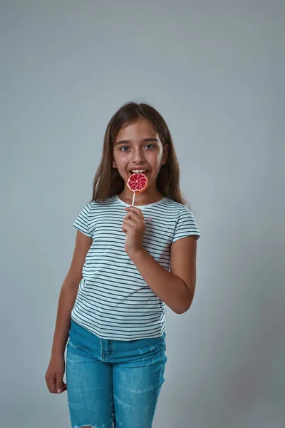 Agradable chica lamer piruleta y mirar a la cámara —  Fotos de Stock