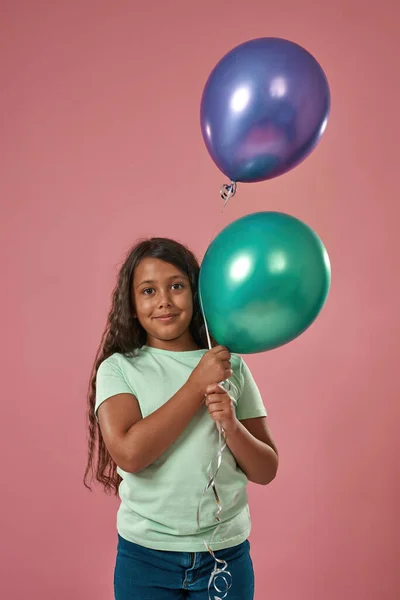 Chica hispana sostiene globos y mira a la cámara —  Fotos de Stock