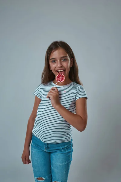 Joyful girl licking lollipop and looking at camera — Stock Photo, Image