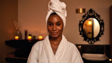 Gülümseyen siyah kız spa salonundaki kameraya bakıyor.