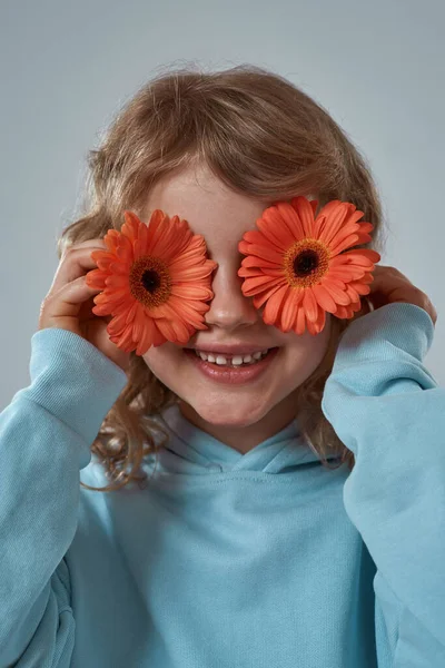Mała dziewczynka pokrywa oczy gerbera kwiaty — Zdjęcie stockowe