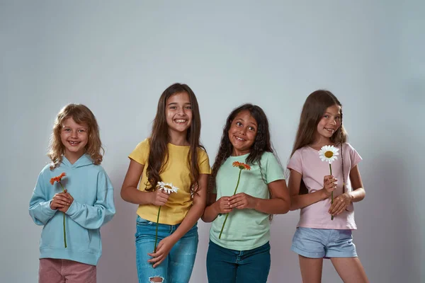 Grupo de niños pequeños con flores mira a la cámara — Foto de Stock