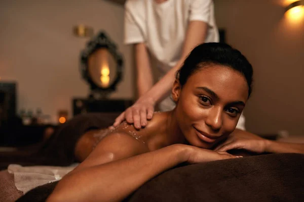 Esfregaço de massagista sal na mulher sorridente de volta à esfoliação — Fotografia de Stock