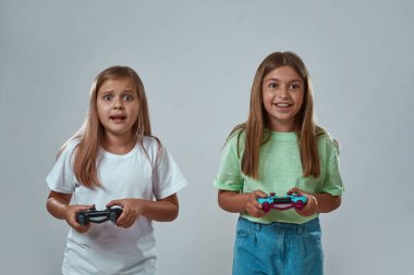 Gri arkaplanda video oyunu oynayan kız arkadaşlar