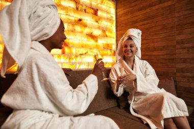 Şampanya içen ve spa salonunda konuşan kadınlar.