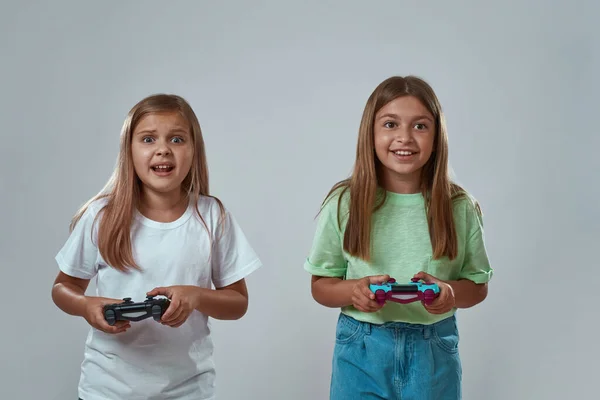 Dua gadis bermain video game pada latar belakang abu-abu — Stok Foto