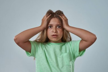 Şok olmuş küçük bir kız kafasına dokunuyor.