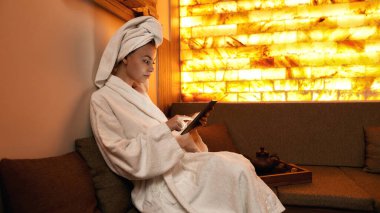 Dijital tableti spa 'da karıştıran bir kızın yan görünümü