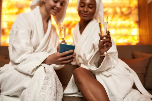 Meninas usam telefone celular e bebem champanhe no spa — Fotografia de Stock