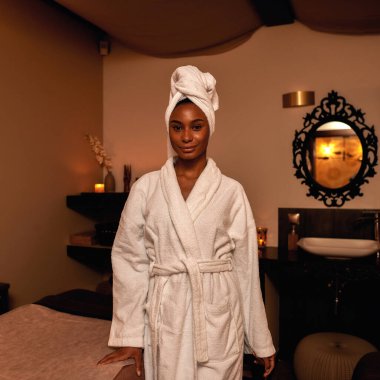 Gülümseyen siyah kız spa salonundaki kameraya bakıyor.