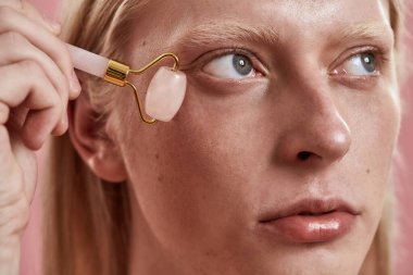 Yüzüne yeşim taşıyla masaj yapan bir adam.