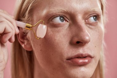 Yüzüne yeşim bigudiyle masaj yapan adama yaklaş.