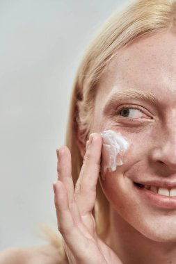 Genç beyaz adam yüzüne kozmetik krem sürmüş.