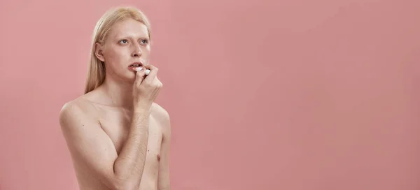 Обрезанный парень красить губы с гигиенической помадой — стоковое фото