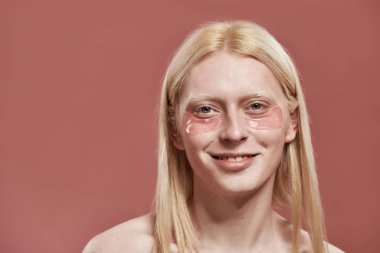 Yüzünde göz bandı olan gülümseyen beyaz adam.