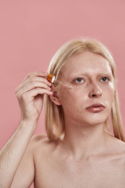 Yüzüne damla damlatan kozmetik yağı damlatan bir adam.