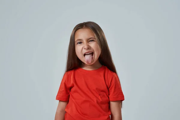 Viccelődő kislány, ahogy kidugja a nyelvét. — Stock Fotó