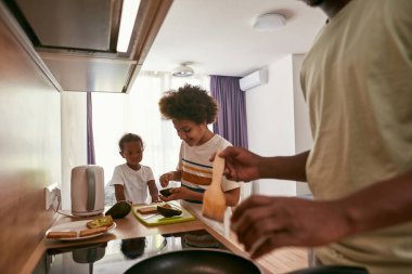 Çocuk tavada kızartılmış ekmeğe kivi sürüyor.