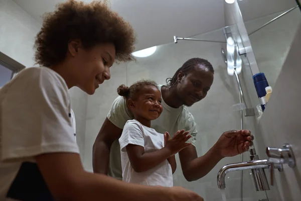 Happy family washing faces in bathroom in morning — Stock Photo, Image