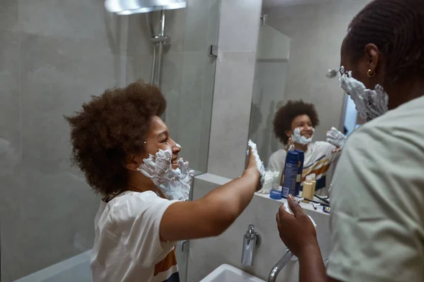 Niño untando la cara del padre con espuma durante el afeitado — Foto de Stock