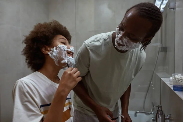 Negro padre mirando a su hijo mientras se afeitan — Foto de Stock