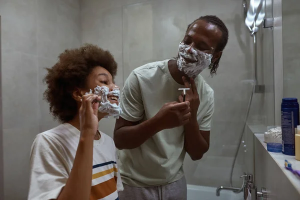 Padre mirando a su hijo pequeño mientras se afeitan — Foto de Stock