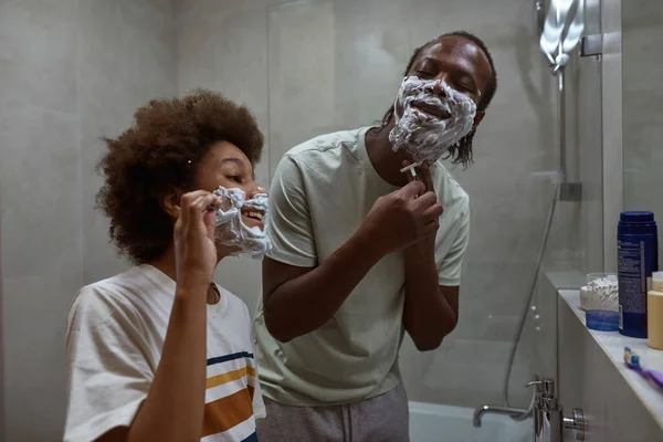 Agradable papá e hijo afeitarse con afeitadora en el baño — Foto de Stock