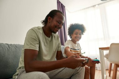 Gülümseyen siyah çocuk, babanın kumandasındaki düğmeye bas.