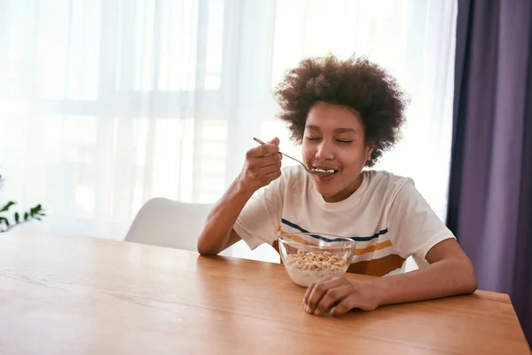 Niño negro con los ojos cerrados disfrutando comiendo cereales —  Fotos de Stock