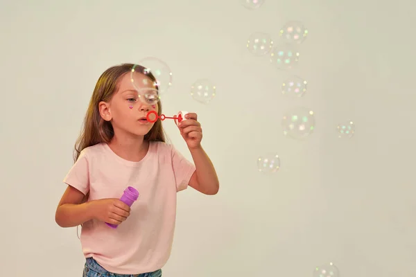 Söt liten flicka blåser såpbubblor i luften — Stockfoto