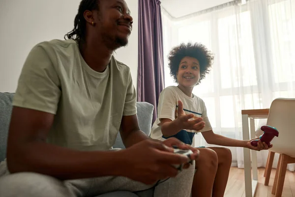 Δυσαρεστημένο αγόρι κοιτά τον μπαμπά ενώ παίζει βιντεοπαιχνίδι — Φωτογραφία Αρχείου