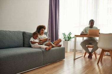 Çocuklar kanepede dinlenirken, babam dizüstü bilgisayarla çalışıyor.