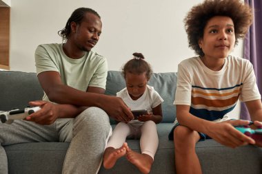 Siyah aile evdeki koltukta aletlerle dinleniyor.