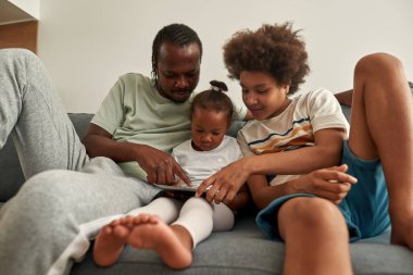 Siyah baba çocuklar için dijital tablet üzerinde işaret etti