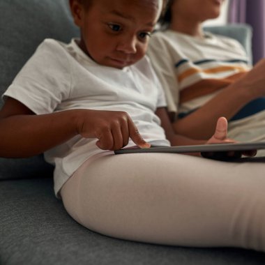 Kardeşinin yanında dijital tablet kullanan bir kız