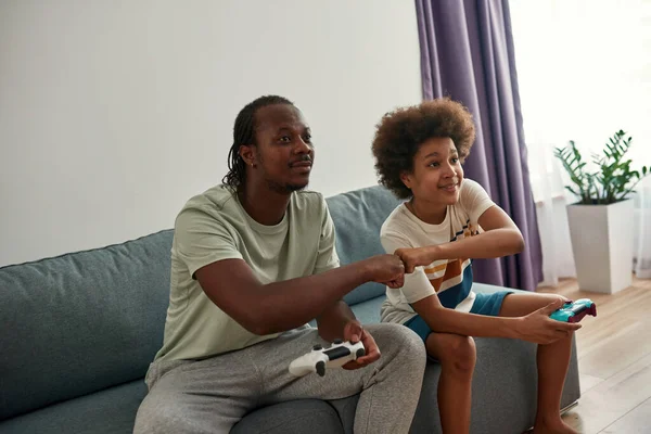 Odaklanmış baba ve oğul yumruk tokuşturup oyun oynuyorlar